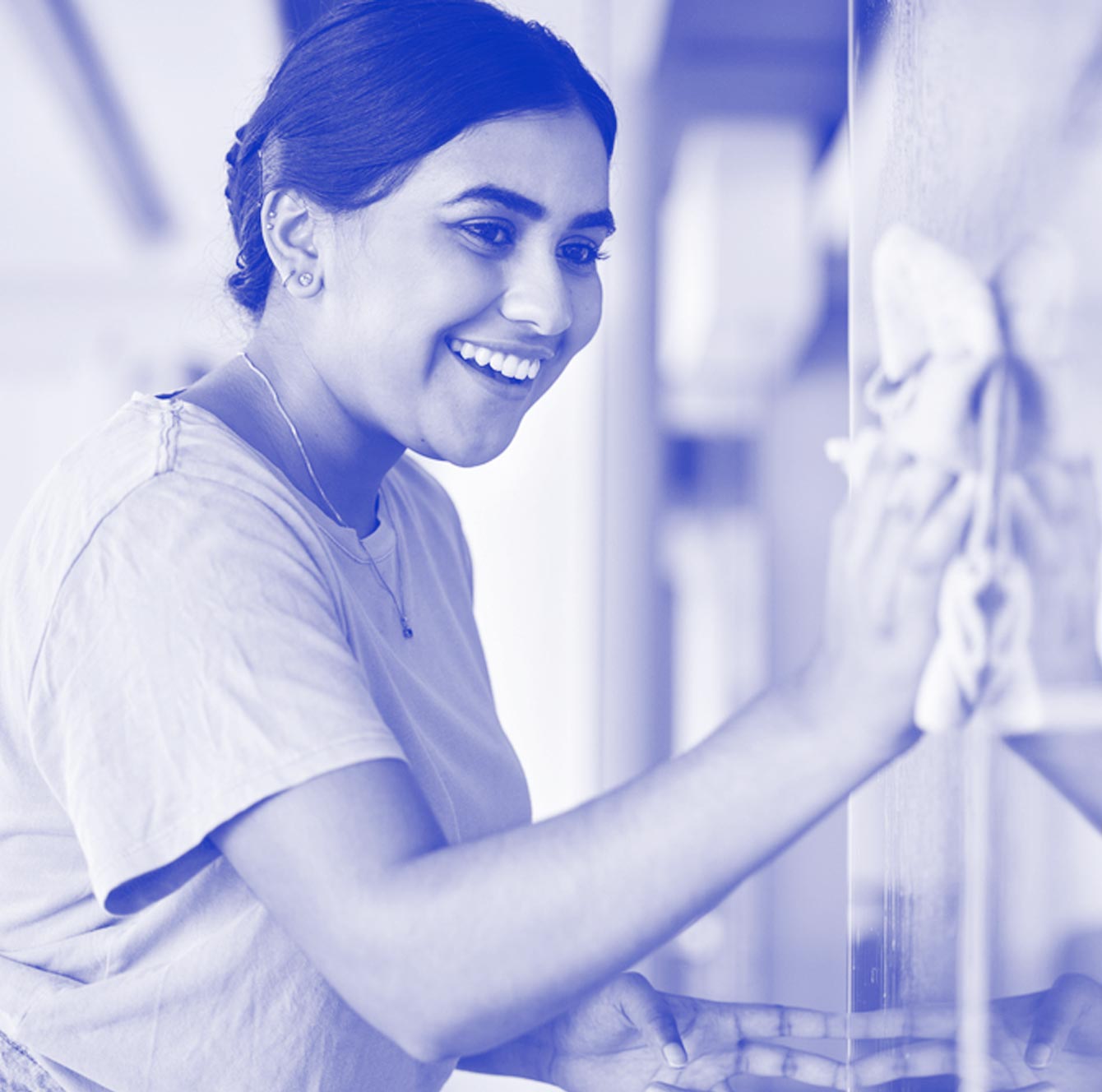 A smiling cleaner wiping down an appliance